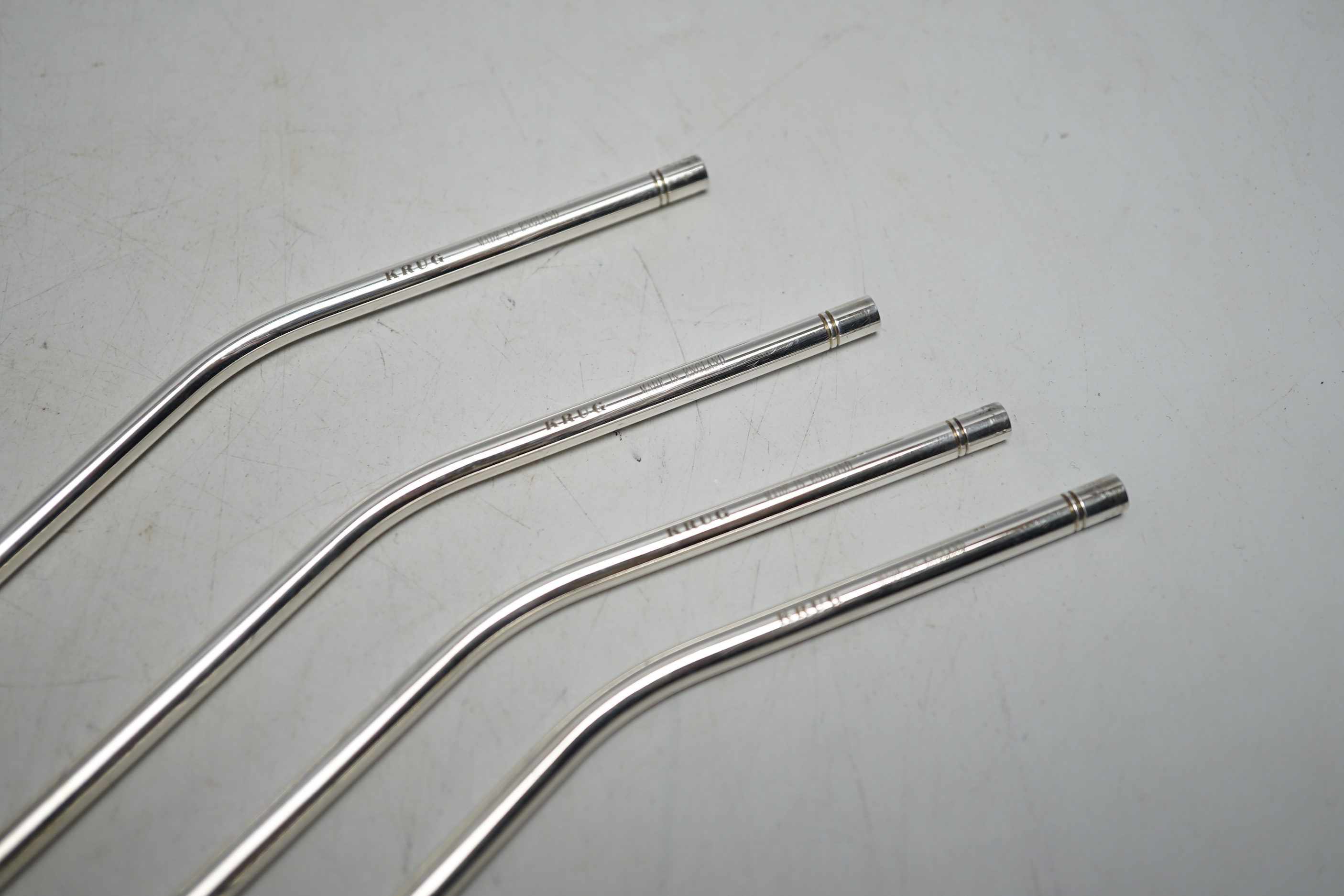 Four modern silver Krug Champagne straws, with original covers, 26.5cm.